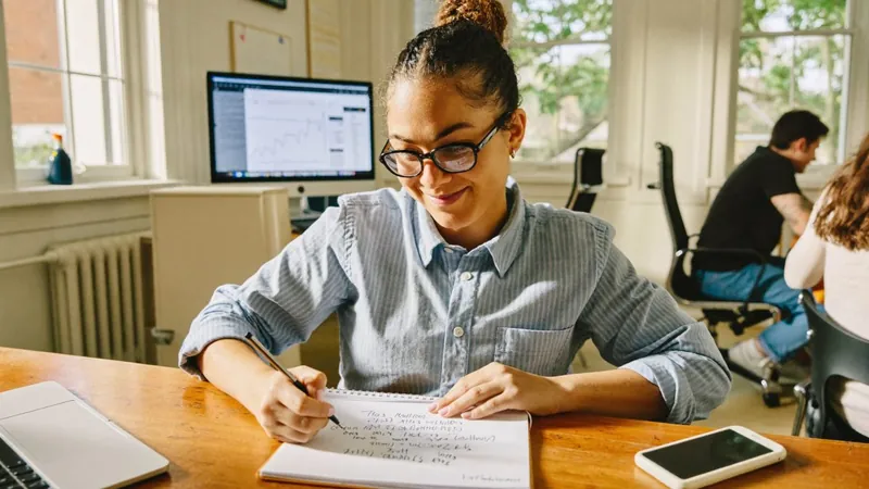 A smiling owner in glasses writing out her plan in a notebook, the Notebook of a COO Foundation Builder Field Guide