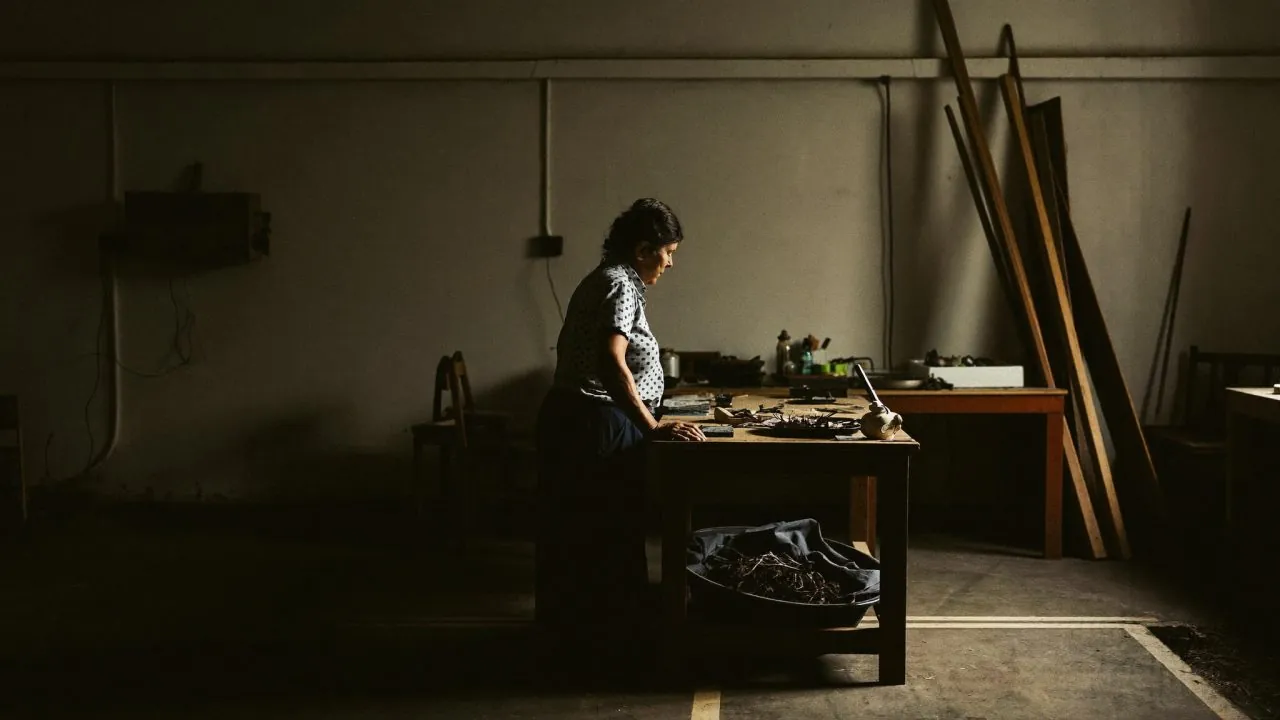 An owner working alone at a bench in a dim workshop, the one person job that Notebook of a COO turns back into a business
